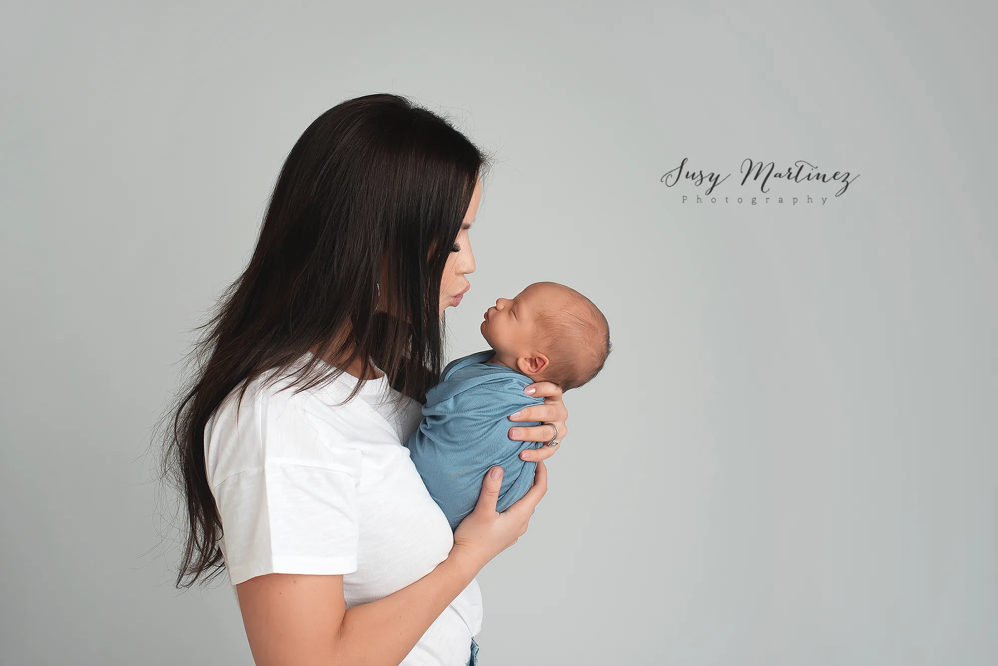 mom kisses baby boy during classic Blue Newborn Mini Session