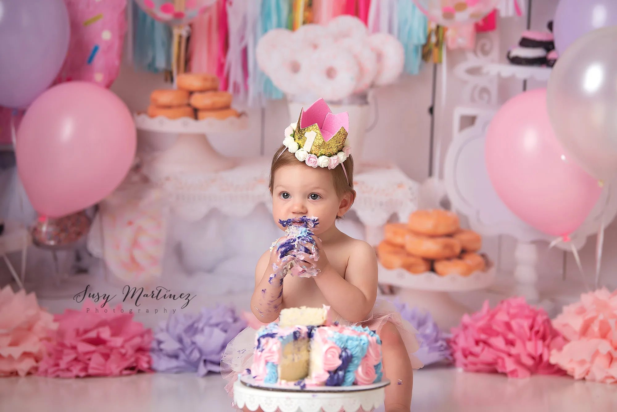baby eats cake with purple icing during pastel cake smash