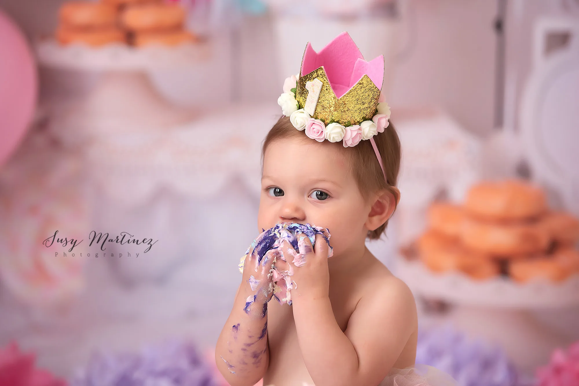 toddler girl eats icing on cake during pastel cake smash