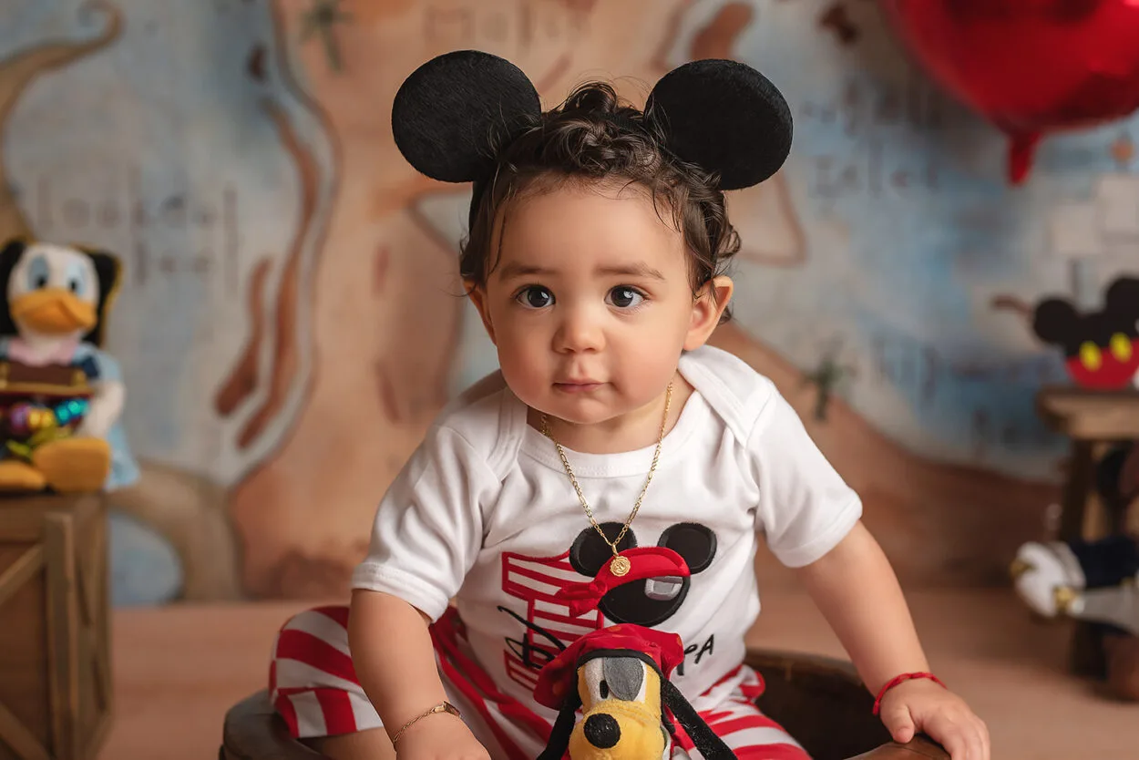 baby boy sits in pirate onesie for first birthday cake smash