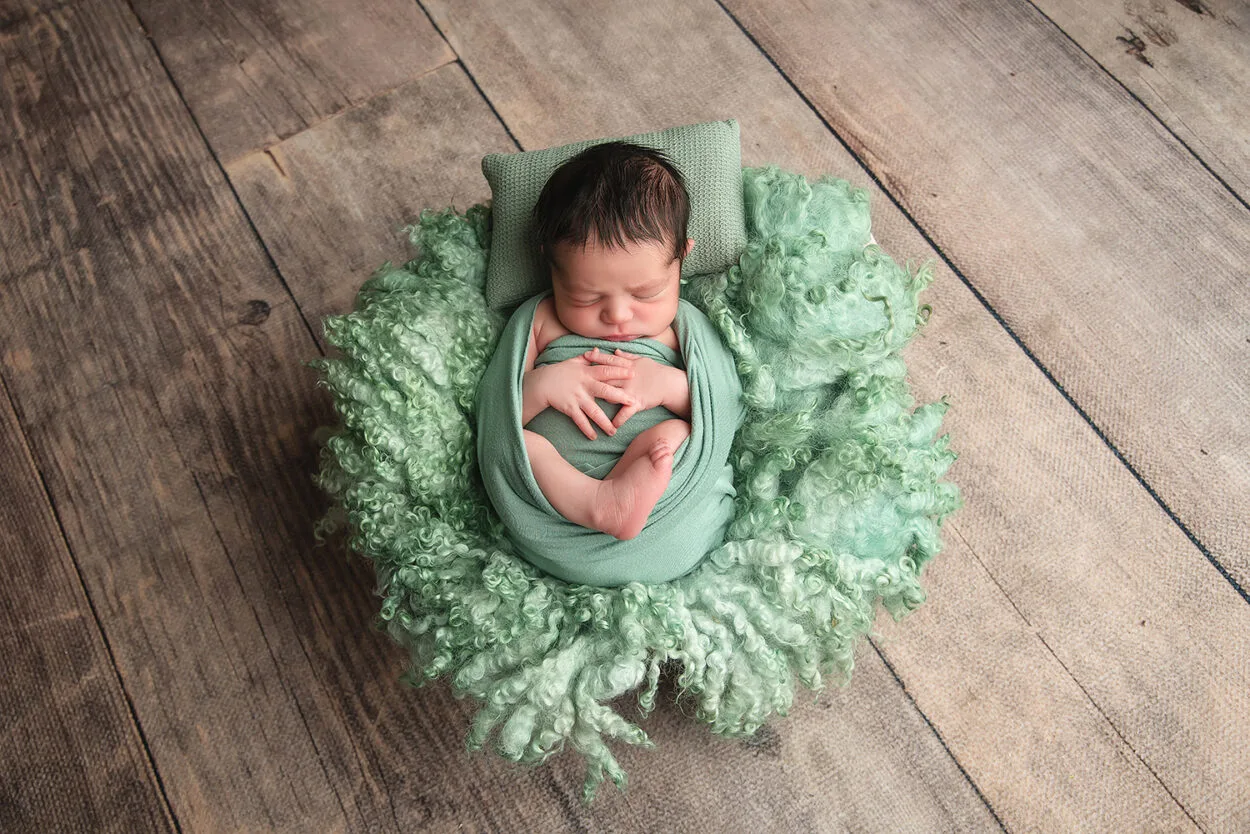 baby boy sleeps in green wrap on a wool layer with Las Vegas photographer 